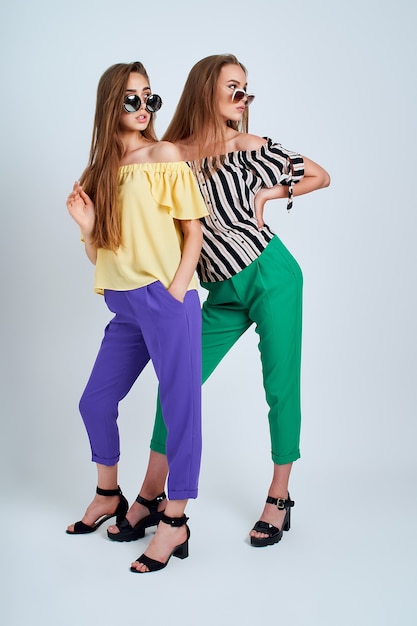 Twee jonge vrouwen in stijlvolle kleding mode schoonheid studio geschoten op een witte achtergrond