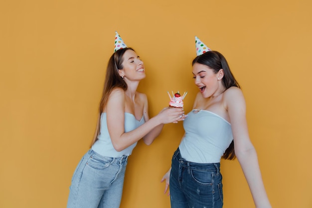 Twee jonge vrouwen in verjaardagshoeden die verjaardag vieren