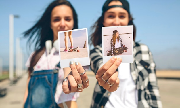 Twee jonge vrouwen laten instant foto's zien met hun longboards