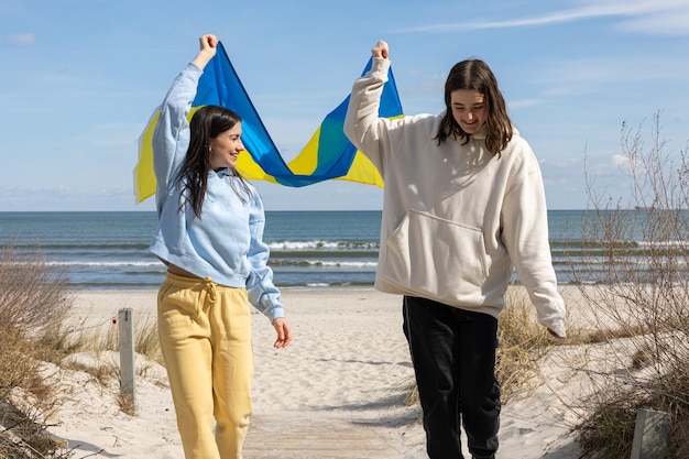 Twee jonge vrouwen met de vlag van oekraïne op de achtergrond van de zee