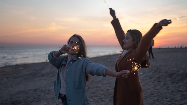 Twee jonge vrouwen met sterretjes in de open lucht. Vrienden met plezier op het strand, geluk en een gevoel van vrijheid, zonsondergang in de schemering