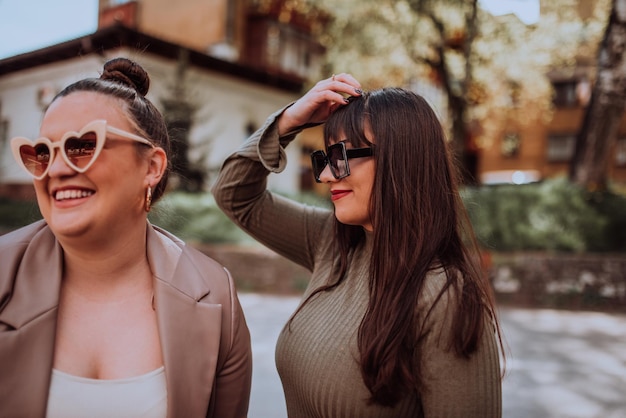 Twee jonge vrouwen omhelzen elkaar emotioneel buiten op een zonnige dag terwijl ze een zonnebril dragen