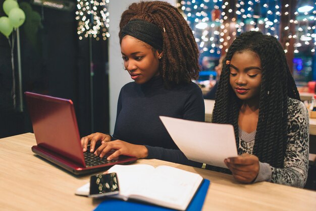 Twee jonge vrouwen studeren aan tafel in café