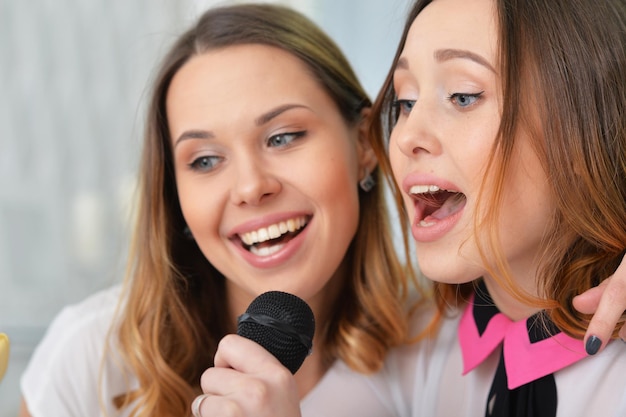 Twee jonge vrouwen zingen karaoke, close-up