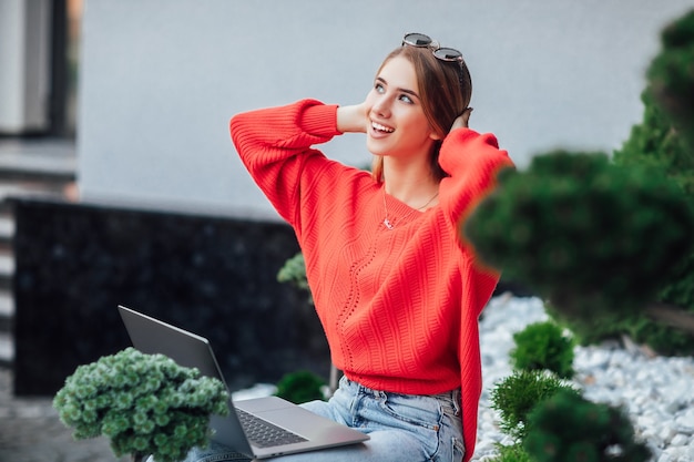 Twee jonge zakenvrouwen die samen lunchpauze hebben op het terras van een coffeeshop, met behulp van laptop en notebook.