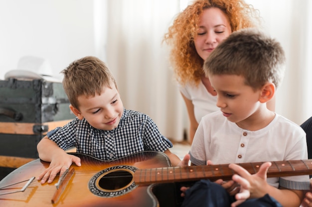 Foto twee jongens die gitaar spelen voor hun moeder