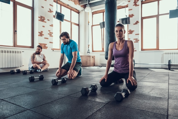 Twee jongens en meisje rusten op gym vloer. Pauze.