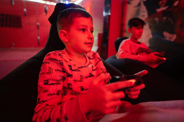Twee jongens gamers spelen gamepad-videogameconsole in rode speelkamer