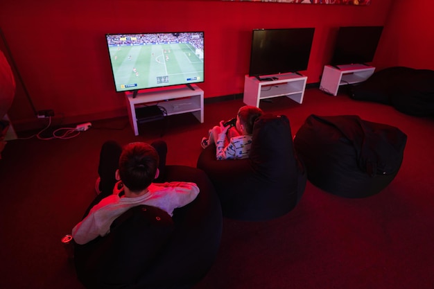 Twee jongens gamers spelen voetbal gamepad videogameconsole in rode speelkamer