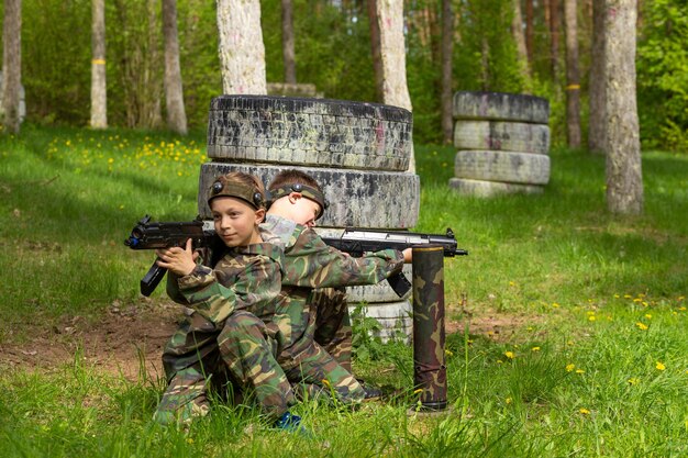 Twee jongens in camouflage die lasergame spelen in een speciale bosspeeltuin