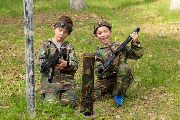 Twee jongens in camouflage die lasergame spelen in een speciale bosspeeltuin