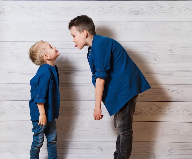 Twee jongens in vrijetijdskleding in witte houten die tongen aan elkaar tonen