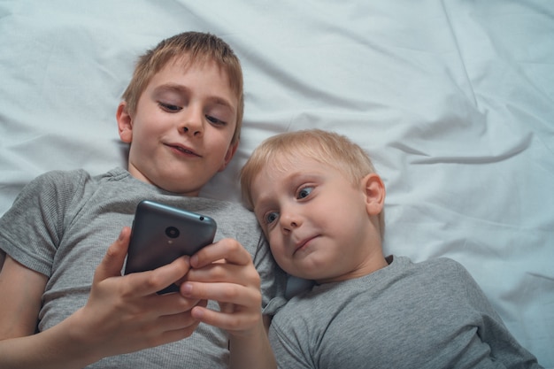 Twee jongens liggen in bed met een smartphone. Gadget Vrije tijd