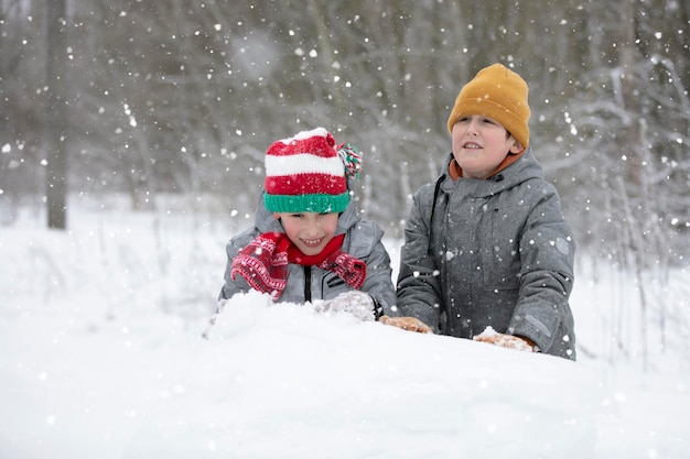 Twee jongens spelen in de sneeuw Kinderen beeldhouwen uit sneeuw Spelen op een winterse dag in de natuur