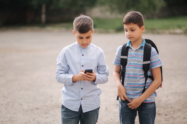 Twee jongens spelen online games in quarantaine. Jonge jongens glimlachen en gebruiken de telefoon. De een ziet hoe de ander speelt