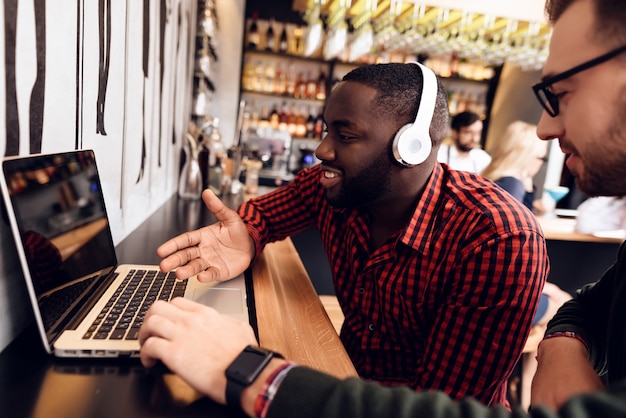 Twee jongens zitten aan de bar met een computer.