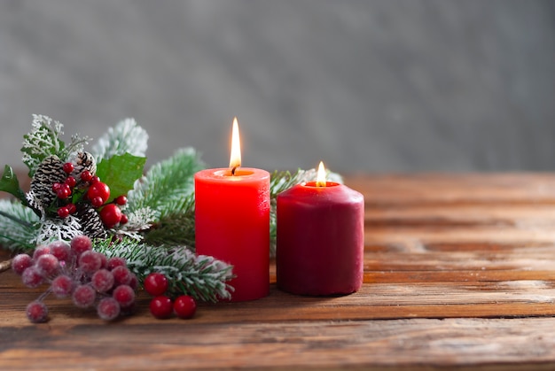 Twee kerst rode brandende kaarsen en tak van kerstboom op de houten