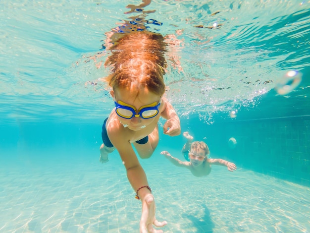 Twee kinderen duiken in maskers onder water in het zwembad.