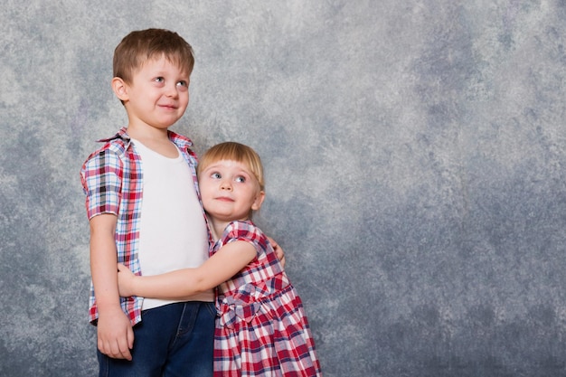 Twee kinderen een jongen en een meisje gekleed in rood geruite kleren knuffelen