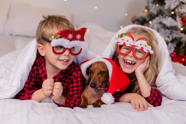 Twee kinderen een jongen en een meisje liggen met kerst in bed met hun geliefde huisdier