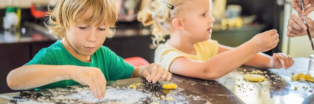 Twee kinderen een jongen en een meisje maken koekjes van deegbanner lang formaat
