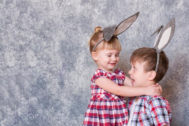 Twee kinderen een meisje en een jongen met paaskonijnenoren op het hoofd lachen en spelen Family Easter Copy space