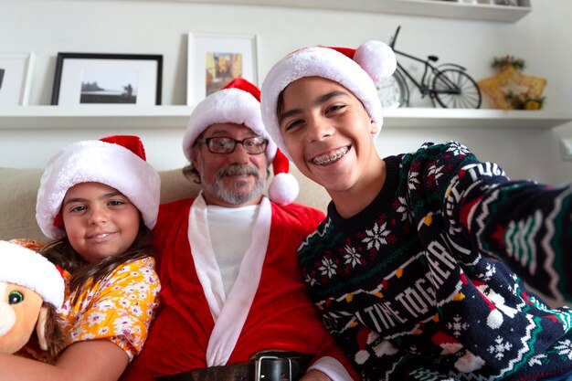 Foto twee kinderen en hun grootvader maken een zelfportret in de kersttijd