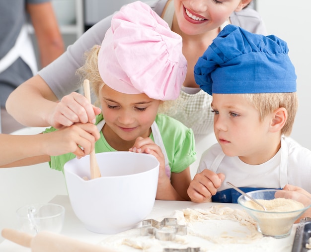 Foto twee kinderen en hun moeder die een voorbereiding voor koekjes samen bewegen