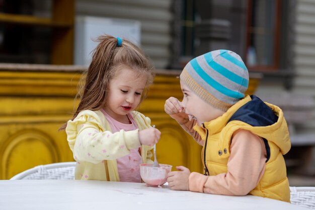 Twee kinderen eten buiten ijs op een zonnige dag