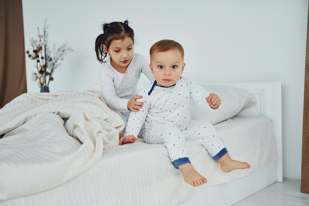 Twee kinderen hebben plezier terwijl ze op bed liggen Interieur en ontwerp van een prachtige moderne slaapkamer overdag