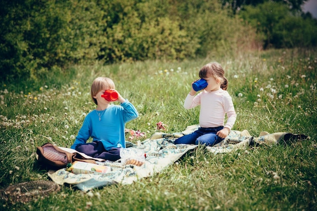 Twee kinderen in de natuur die uit bekers drinken