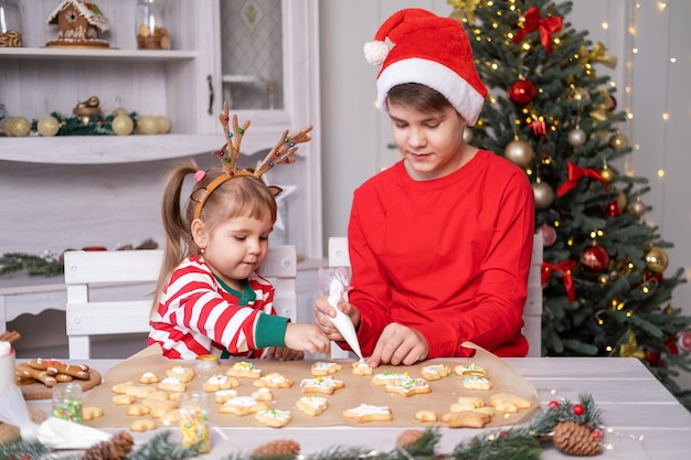 twee kinderen jongen en meisje in pyjama feestelijke peperkoek koken in kerst versierde keuken
