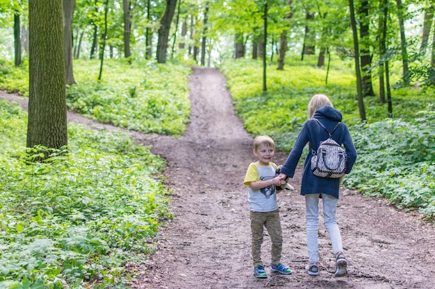 Twee kinderen lopen over een bospad De zus en de jongere broer gaan de weg op in het bos