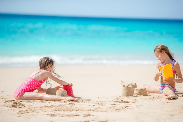 Twee kinderen maken zandkasteel en plezier op tropisch strand