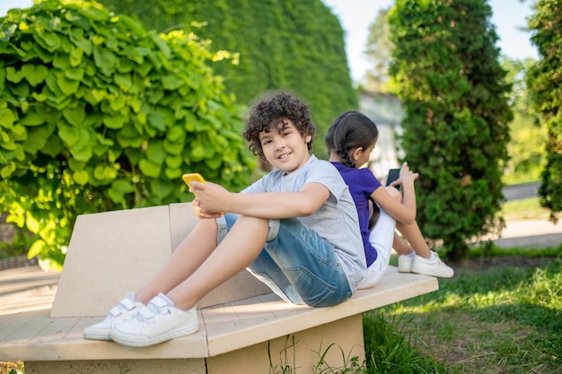 Twee kinderen met mobiele telefoons in het park