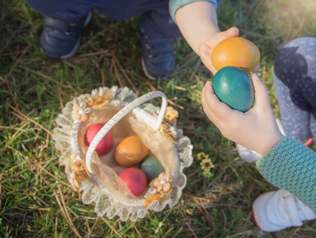 Twee kinderen overhandigt detail die hun paaseieren tonen alvorens hen in de mand op de tuin te zetten