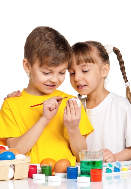 Twee kinderen schilderen paaseieren geïsoleerd op een witte achtergrond