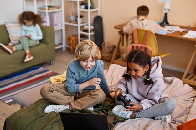 Twee kinderen spelen een videogame op bed