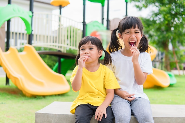 Twee kinderen spelen en eten lolly's op de speelplaats