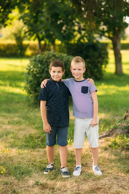 Twee kinderen spelen in het park. twee mooie jongens in t-shirts en korte broeken hebben plezier met glimlachen. ze eten ijs, springen, rennen. de zomer is zonnig.