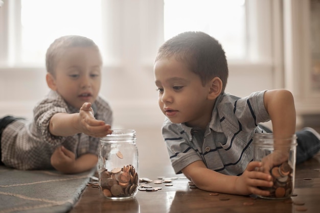 Twee kinderen spelen met munten die ze in glazen potten laten vallen