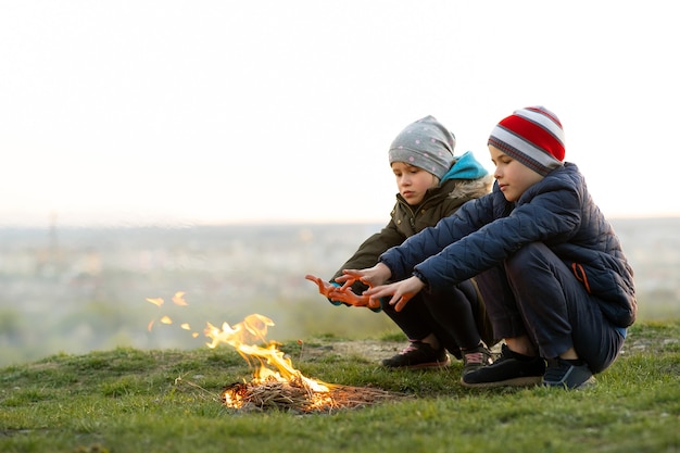 Twee kinderen spelen met vuur buiten bij koud weer.