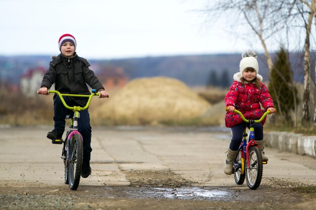 Twee kinderenjongen en meisjes berijdende fietsen bij koud weer