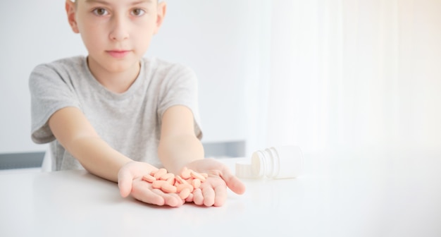 Twee kinderhanden handvol witte tabletten, drugs en medicijnen veiligheids- en consumptieconcept met kopieerruimte