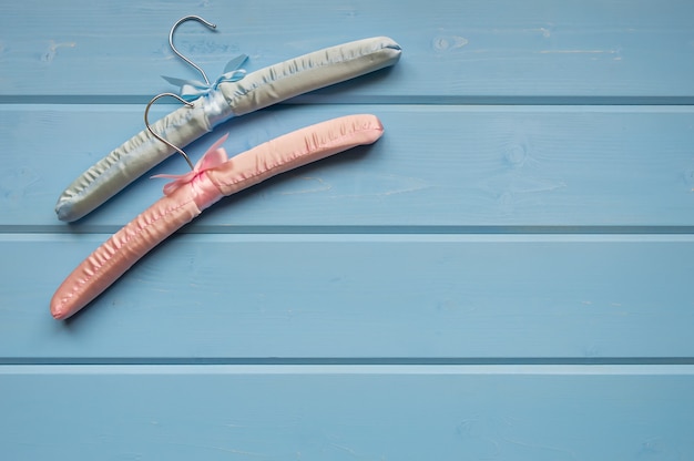 Twee kleerhangers liggen op een blauwe houten achtergrond. Bekijk van bovenaf een plek voor tekst.