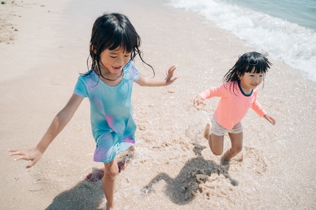 Twee kleine Aziatische meisjes spelen op het strand