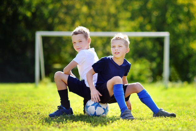 Twee kleine broers die pret hebben die een voetbalspel op zonnige de zomerdag spelen