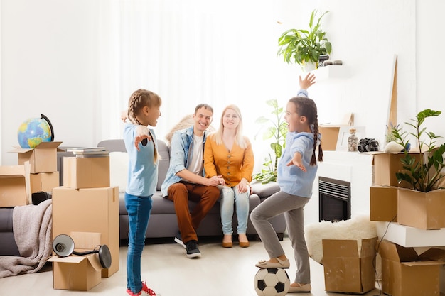 twee kleine dochters vieren verhuisdag, opgewonden door verhuizing naar nieuw huis, lachende woonkamer met kartonnen dozen