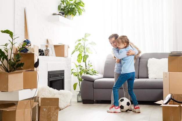 twee kleine dochters vieren verhuisdag, opgewonden door verhuizing naar nieuw huis, lachende woonkamer met kartonnen dozen