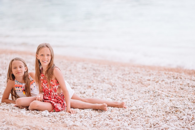 Twee kleine gelukkige meisjes hebben veel plezier op tropisch strand samen spelen